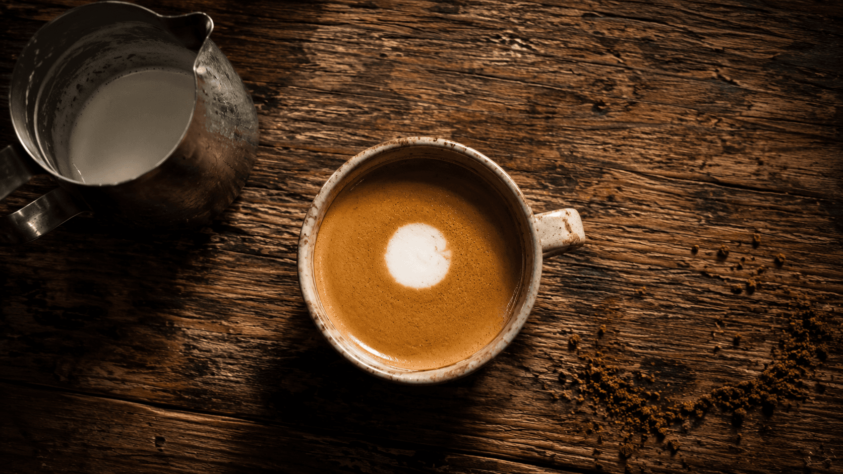 First latte art pour attempt — a simple white dot forming on espresso